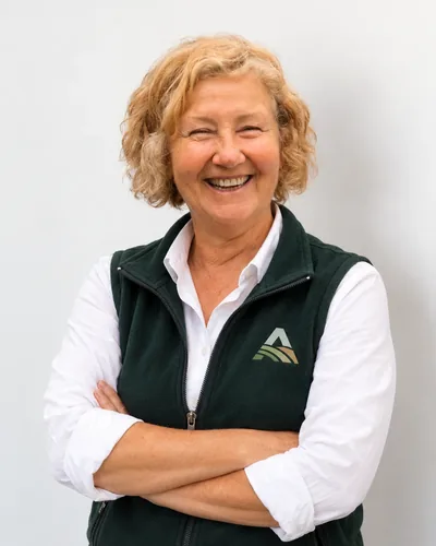 Ana María Robles, contadora de Altos de San Isidro, sonriendo con el chaleco del barrio